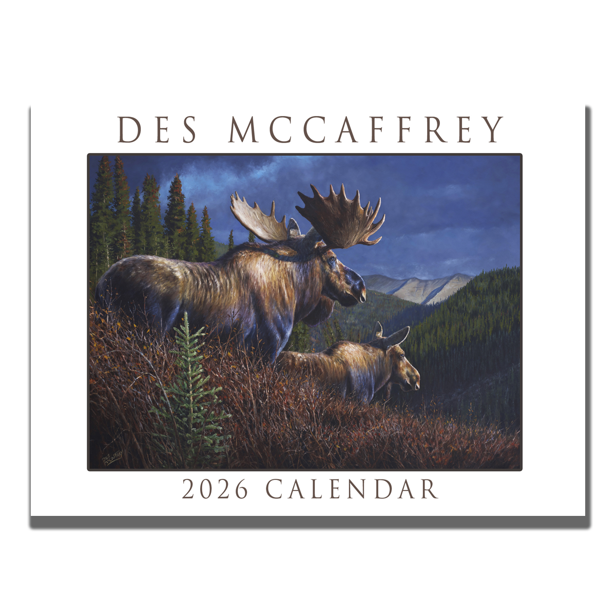 2026 wall calendar by wildlife artist Des McCaffrey featuring a cover illustration of two moose in an autumn mountain landscape, shown on a rustic wooden surface with paintbrushes and tubes of oil paint.