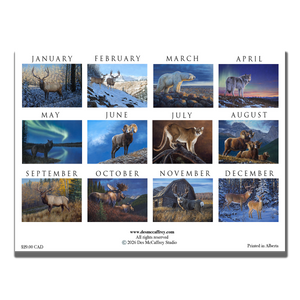 2026 wall calendar by wildlife artist Des McCaffrey featuring the back cover illustrations of several big game animals, shown on a rustic wooden surface with paintbrushes and tubes of oil paint.