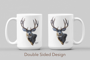 White ceramic coffee mug featuring a painting of a trophy mule buck, artwork by Canadian wildlife artist Des McCaffrey, both sides displayed.